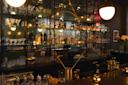 A dimly lit, elegant bar with mirrored shelves displaying various liquor bottles and glasses. Warm lighting creates a cozy ambiance, with decorative elements like flowers and candles enhancing the sophisticated atmosphere.