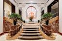 Grand hotel lobby with a central staircase flanked by two curved marble staircases.