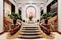 Grand hotel lobby with a central staircase flanked by two curved marble staircases.