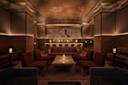 Dimly lit upscale bar with modern decor. Central, illuminated bar with geometric wall pattern. Soft lighting under a textured ceiling and cozy seating surrounds low tables, creating an intimate atmosphere.