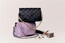 Two stylish handbags are displayed: one black with gold studs and chain strap, and one purple with a textured pattern and black chain. They are stacked, with a hammer and scattered small metal pieces beside them on a neutral background.