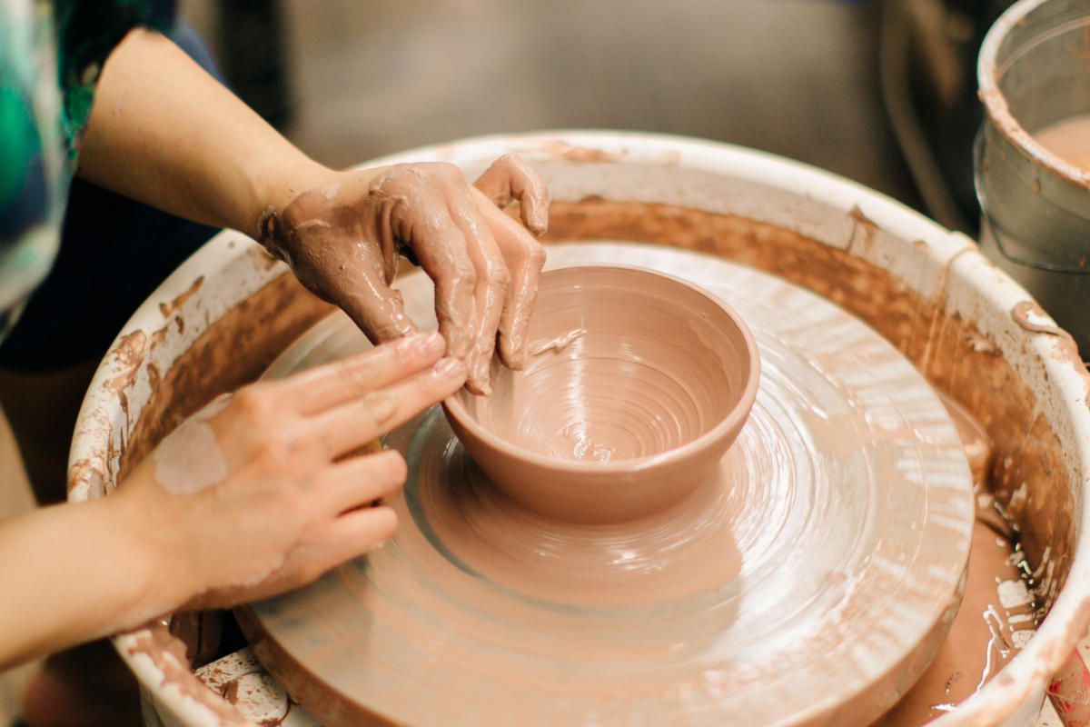 Close-up of hands throwing a brown clay bowl on a pottery wheel 