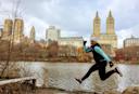 A person jumps while looking at the camera, in Central Park