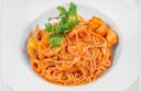 A plate of spaghetti in a rich tomato sauce, garnished with fresh parsley and pieces of shrimp, served in a white bowl.