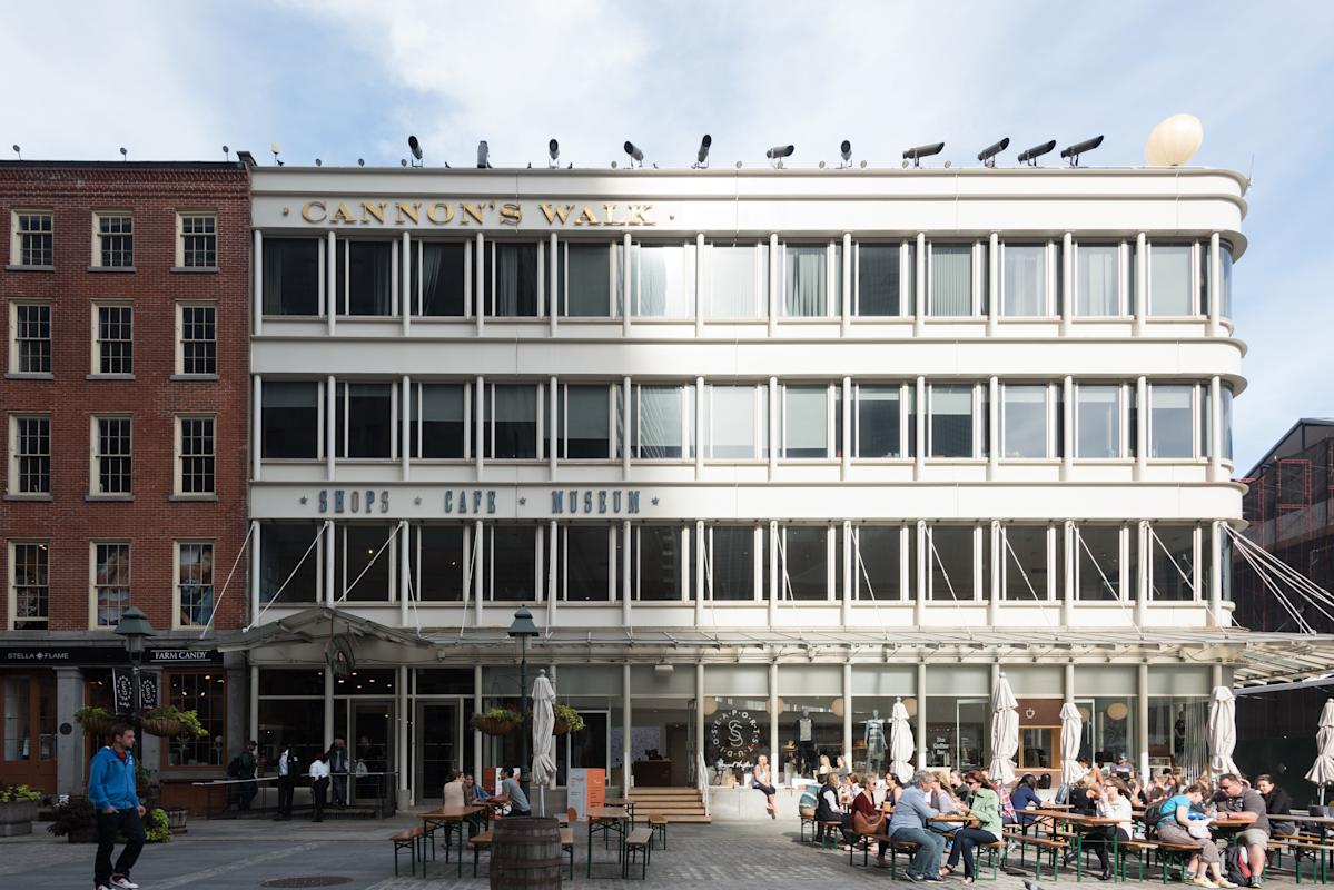 Cannon's walk building and people seating at outdoor benches in Seaport, NYC