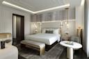 A modern, elegant hotel bedroom features a large bed with white linens, decorative pillows, bedside tables with flowers, gold accents, soft lighting, a bench, armchair, round marble table, and contemporary decor.