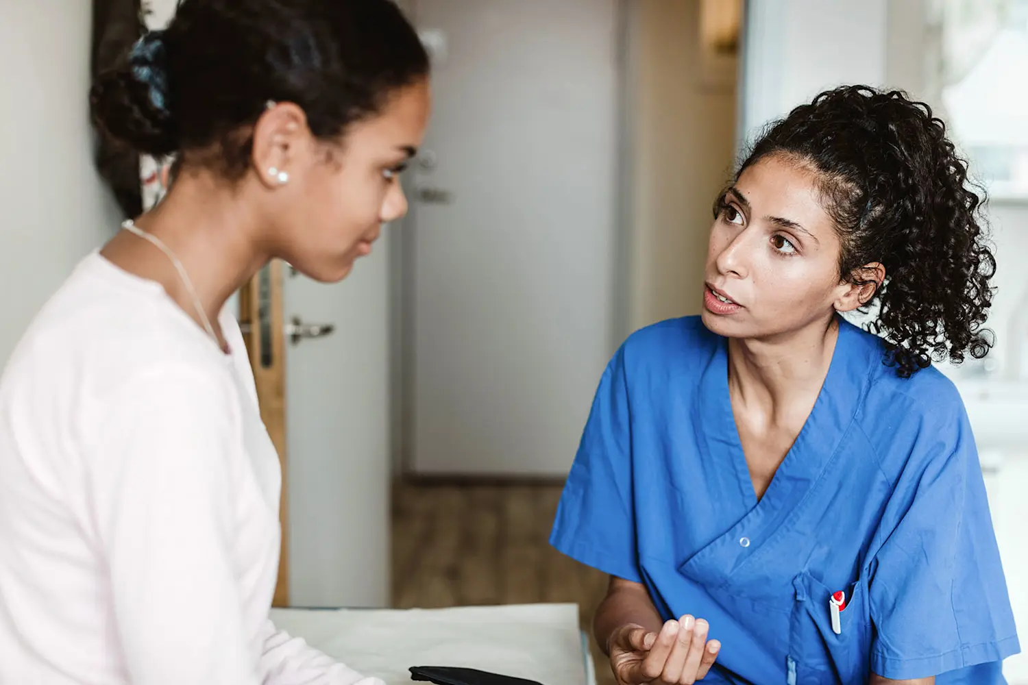 A nurse is taking care of a young woman, seem to be giving some sort of instructions