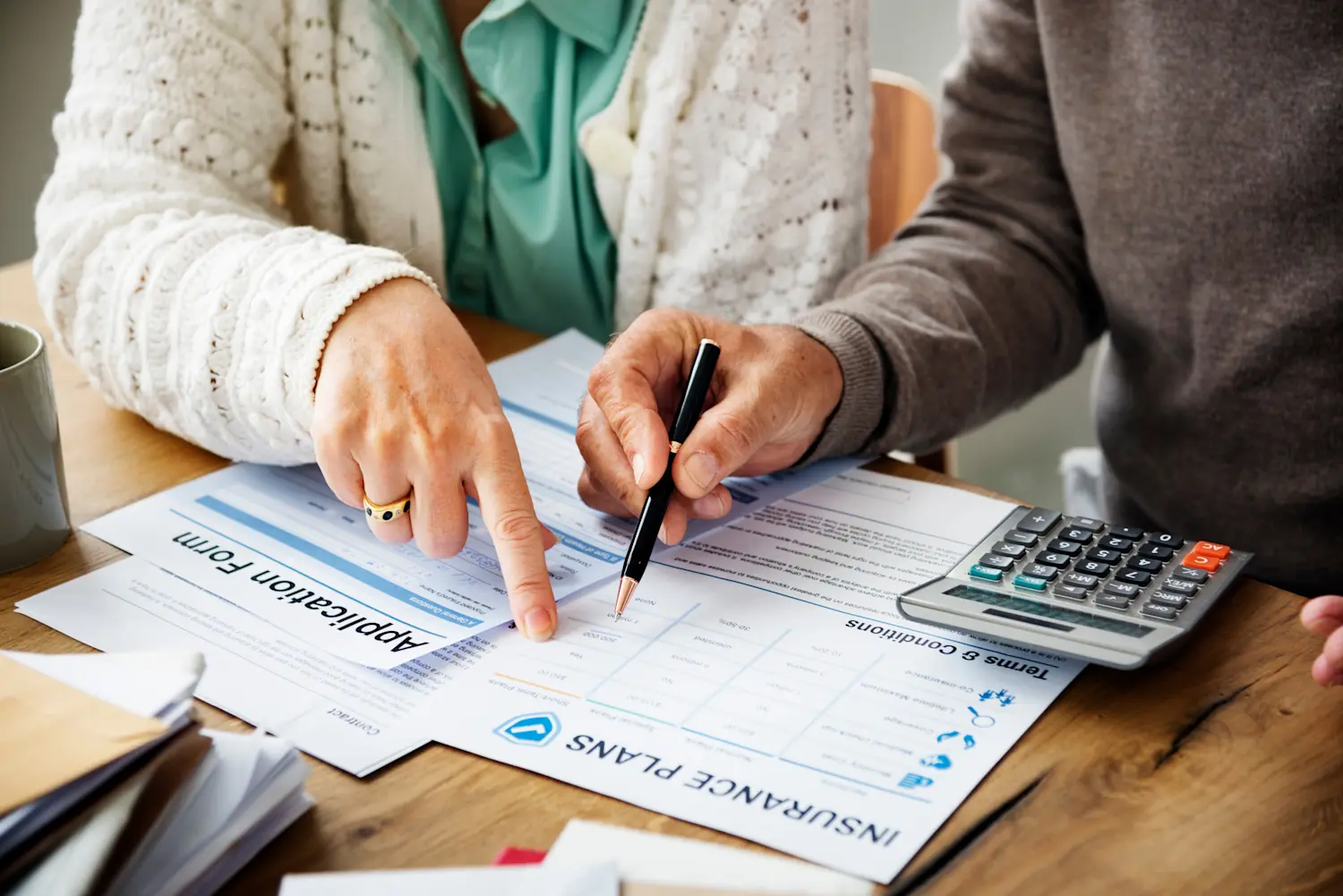 Two people reviewing insurance plans with a calculator