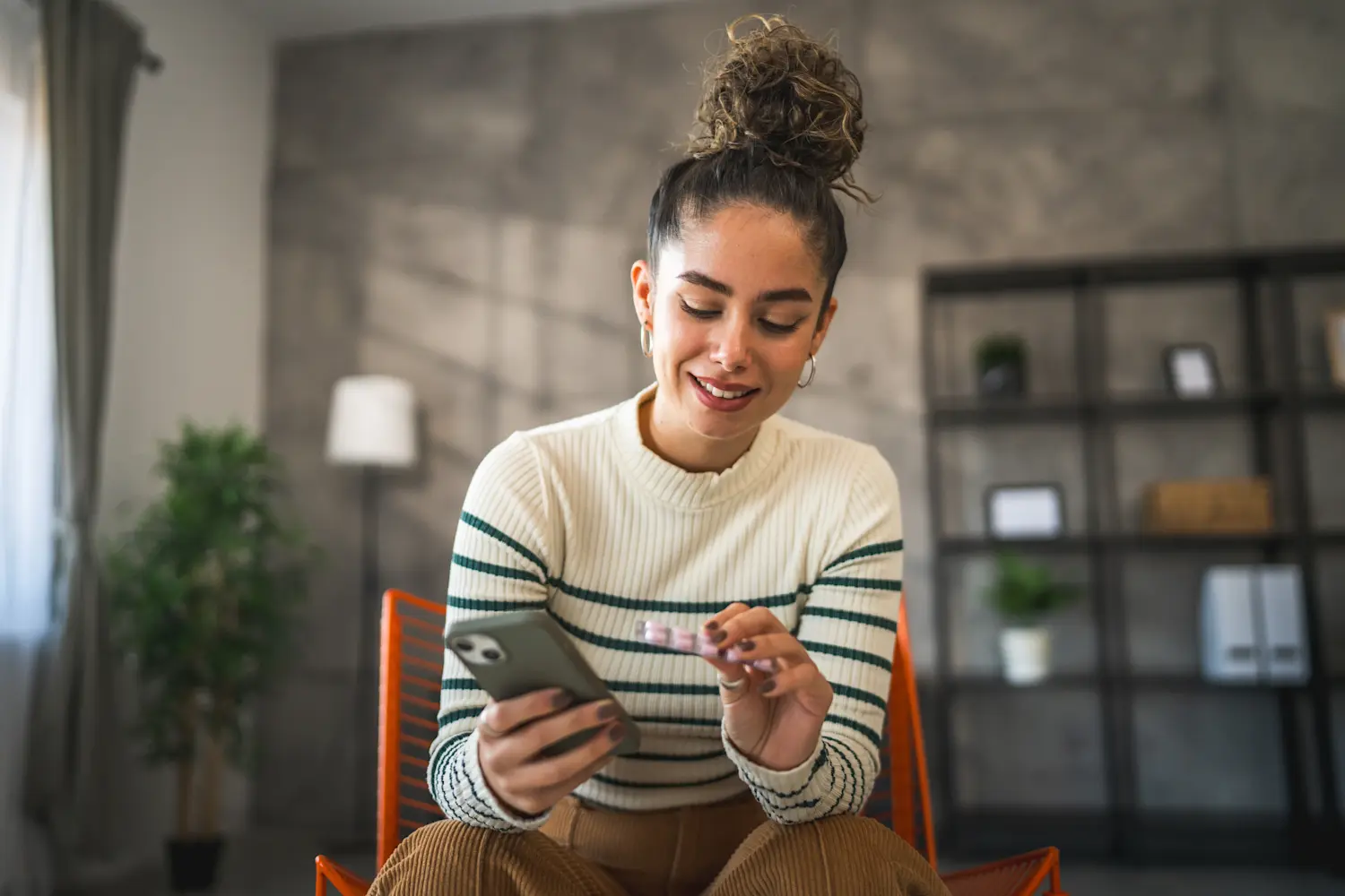 woman holding phone and looking at medication