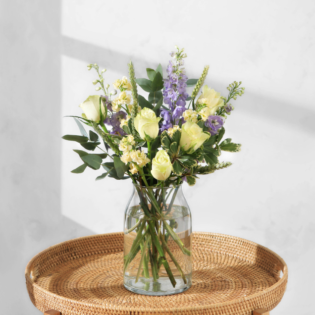 The Jazz timeless bouquet by Bloom & Wild arranged in a glass vase, featuring classic white and lilac stems