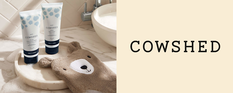 Two tubes of Cowshed bath products on a marbled bathroom countertop. 