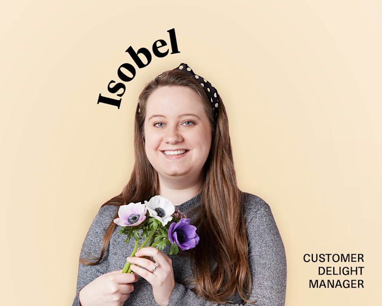 Isobel, Bloom & Wild's Customer Delight Manger, stands smiling while holding a small posy.