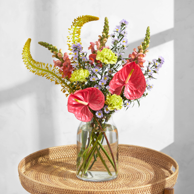 The Vaesna standout bouquet by Bloom & Wild arranged in a glass vase, featuring large and unique looking flowers and stems