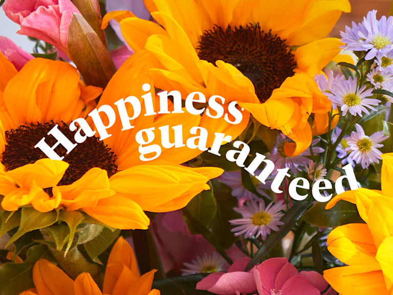 The words 'Happiness guaranteed' appear in front of a vivid sunflower bouquet.