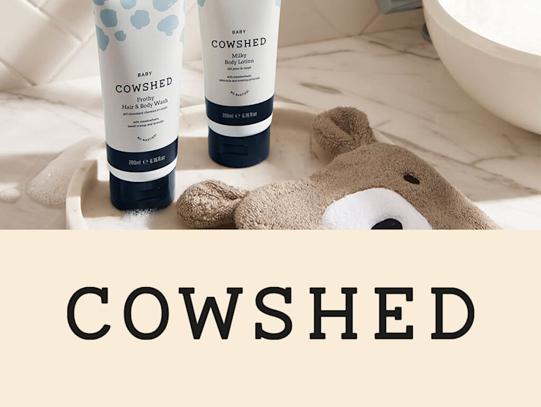 Two tubes of Cowshed bath products on a marbled bathroom countertop. 