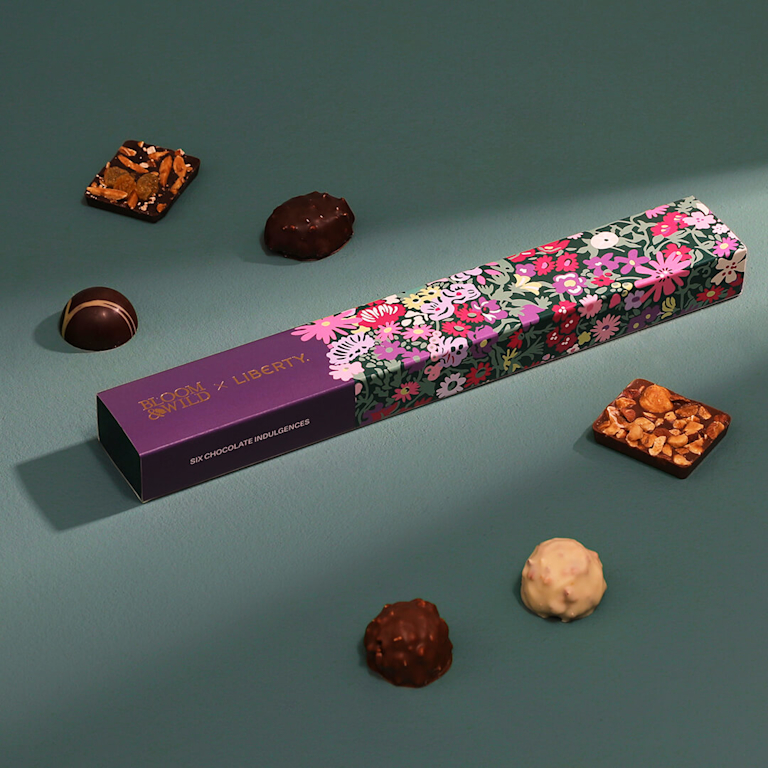 A box, decorated with a Liberty print, sits in the middle of assorted chocolates.