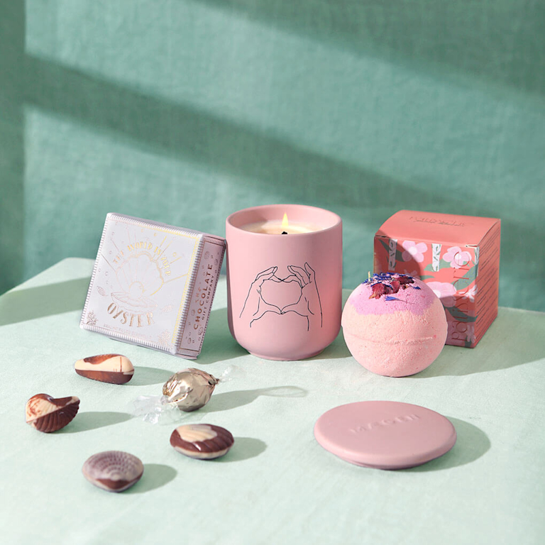 The Moment of Calm Bundle on a light green background. Including a candle, a bath bomb and some chocolates