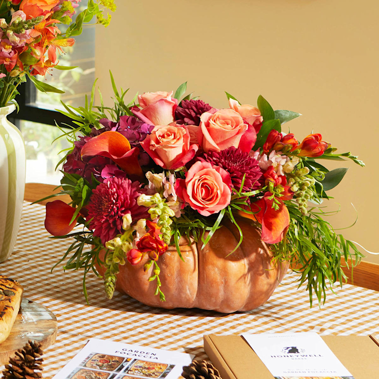 A beautiful mix of orange-toned stems arranged in a pumpkin.
