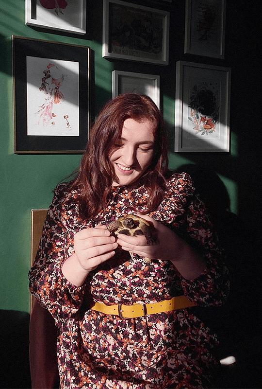 Alice holds one of her tortoises and looks lovingly down at it.
