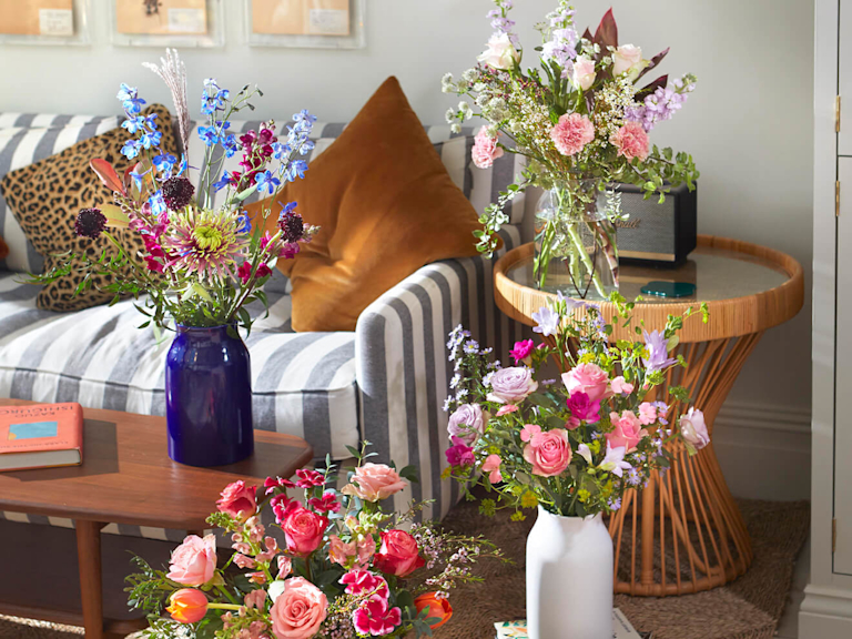 A variety of bouquets (some that are softly shaded and others that are bright and bold) are dotted around a living room.