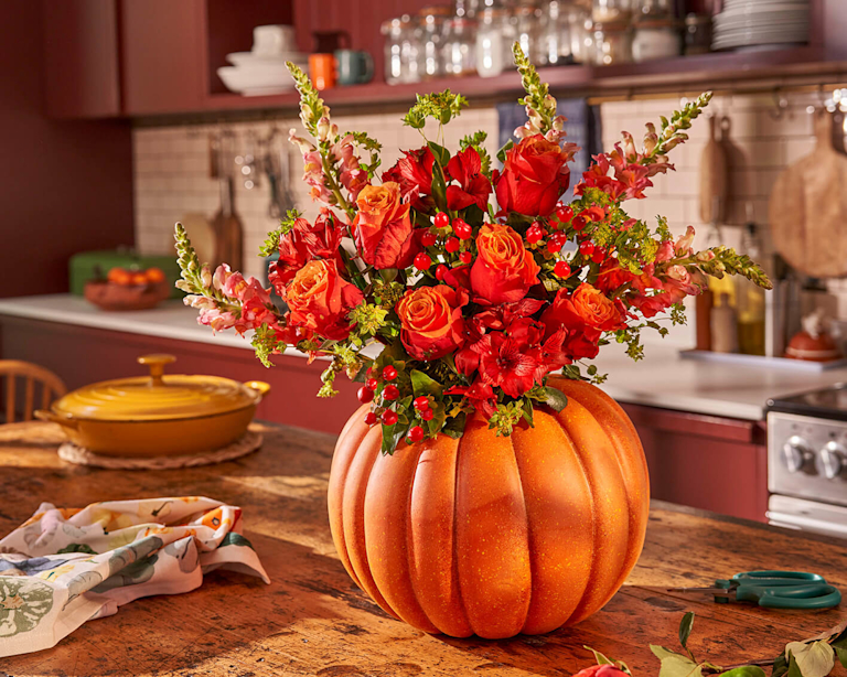 The Orla bouquet – orange and red autumnal flowers – bursts from a pumpkin.