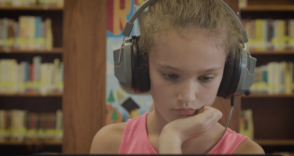 girl with headphones in front of a computer