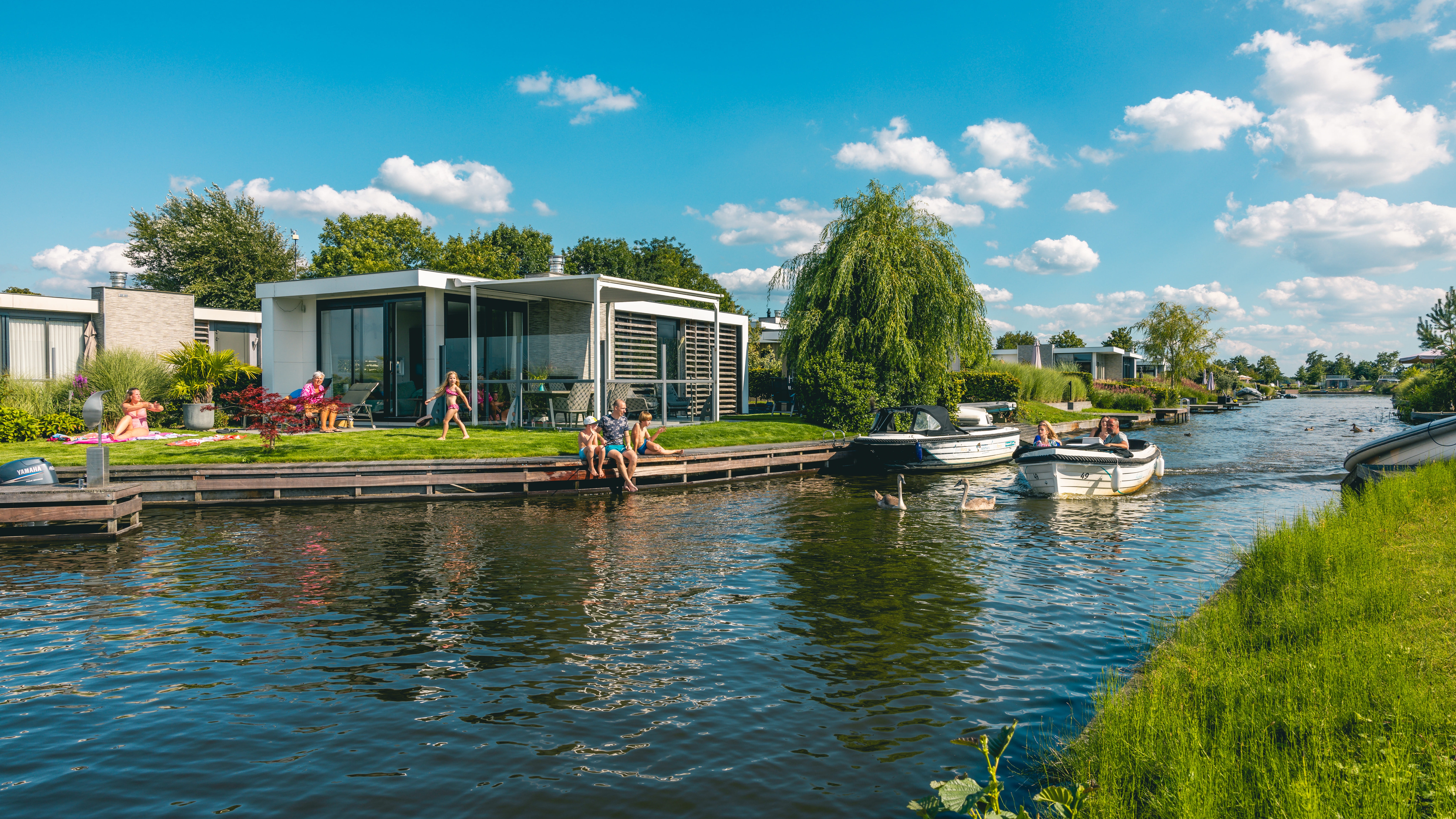 EuroParcs Veluwemeer holiday house at the water family in garden boat passes by 