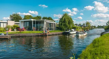 EuroParcs Veluwemeer holiday house at the water family in garden boat passes by 