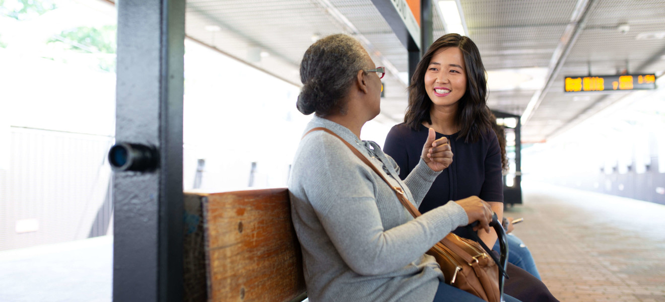 Michelle Wu speaking to a T rider at an Orange Line Stop.