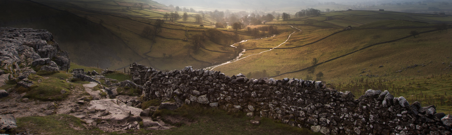 Sunrise over Malham Cove and Dale in Yorkshire Dales National Park with sunlight bursting through mist