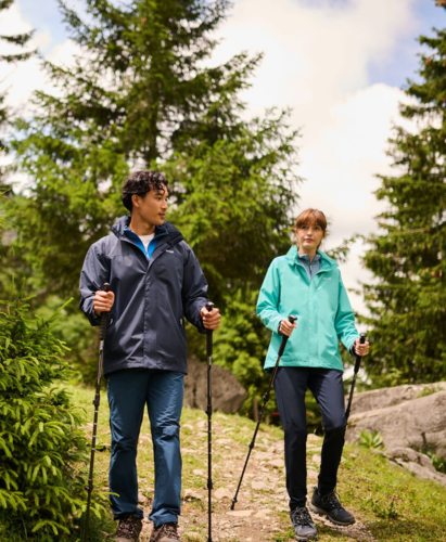 Two people walking in the woods using walking poles