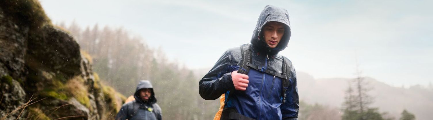 Two men hiking in the rain wearing waterproof coats treated with durable water repellent