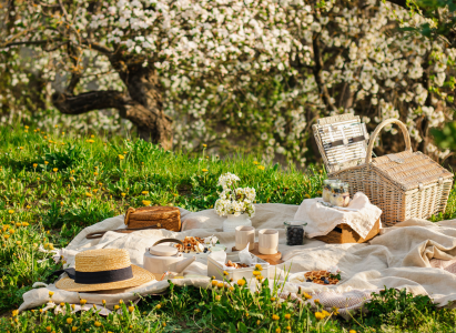 Breakfast picnic with waffles and tea in spring blossom garden on a white tablecloth on a sunny day