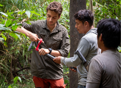 Dael is wrapping some tape around a piece of scientific equipment in the Amazon Rainforest