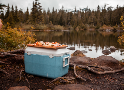 A camping cooler by the waterside with a summer charcuterie board