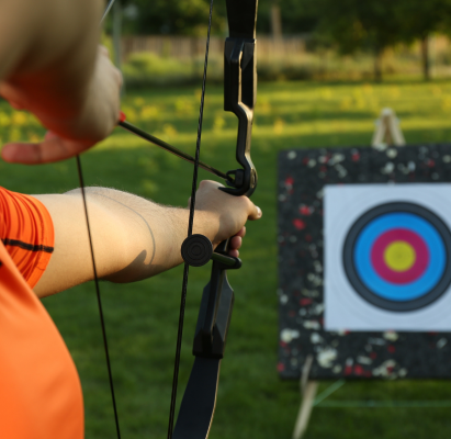 Man with bow and arrow aiming at archery target in park, closeup