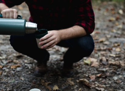 Camper pouring coffee from a thermos flask