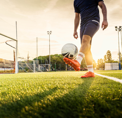 Professional footballer kicking ball in stadium