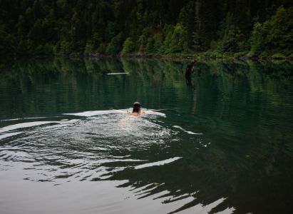 A young woman swimming in a lake on a smoky evening. Wild swimming.