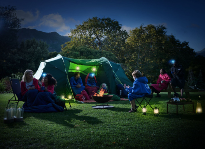 A family sat around a camping tent at night