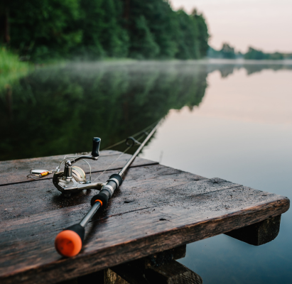 Fishing rod, spinning reel on the background pier river bank.