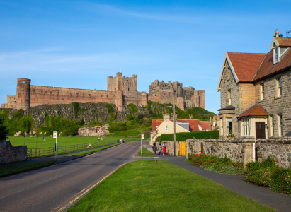 The imposing Bamburgh Castle standing tall over the town of Bamburgh in Northumberland, UK.