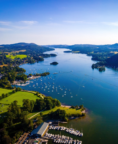 Aerial view of Windermere in the Lake District, Cumbria, England, showcasing a wide, serene lake surrounded by green hills and countryside.