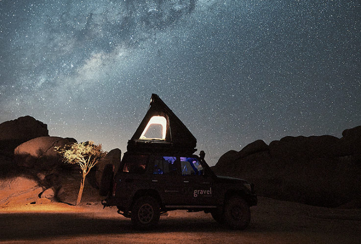 Illuminated Car silhouetted by Starry Night Sky