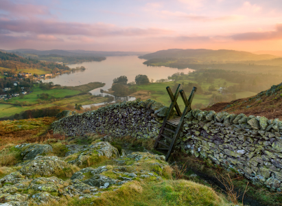 Beautiful sunset over Windermere in the Lake District with a stile and stone wall in the foreground.