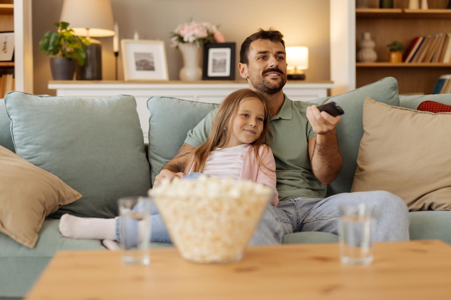 A parent and child watching TV together.