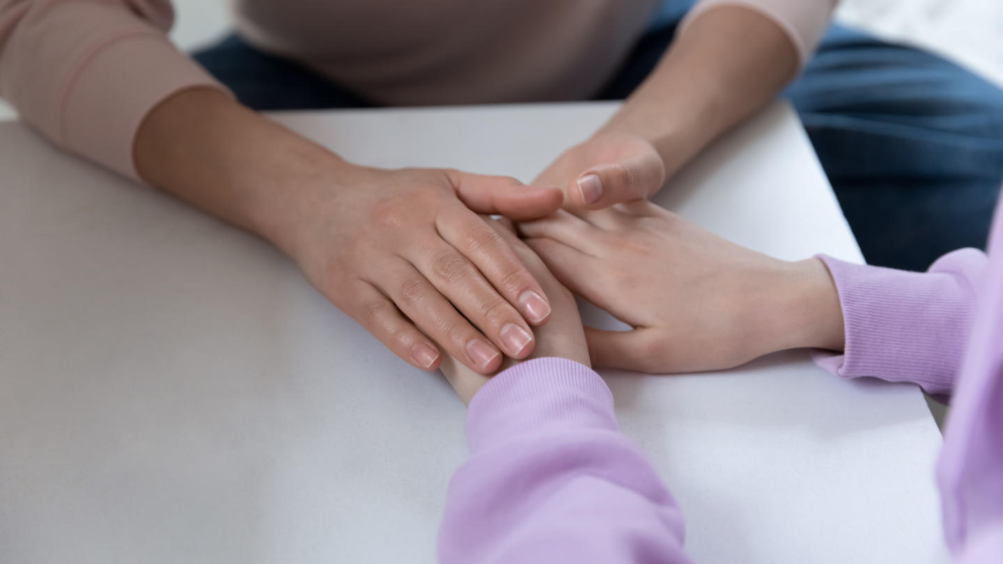 Close up of caring mom holding teenagers hands showing support