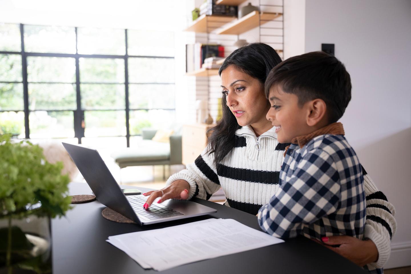 A parent and child using a laptop.