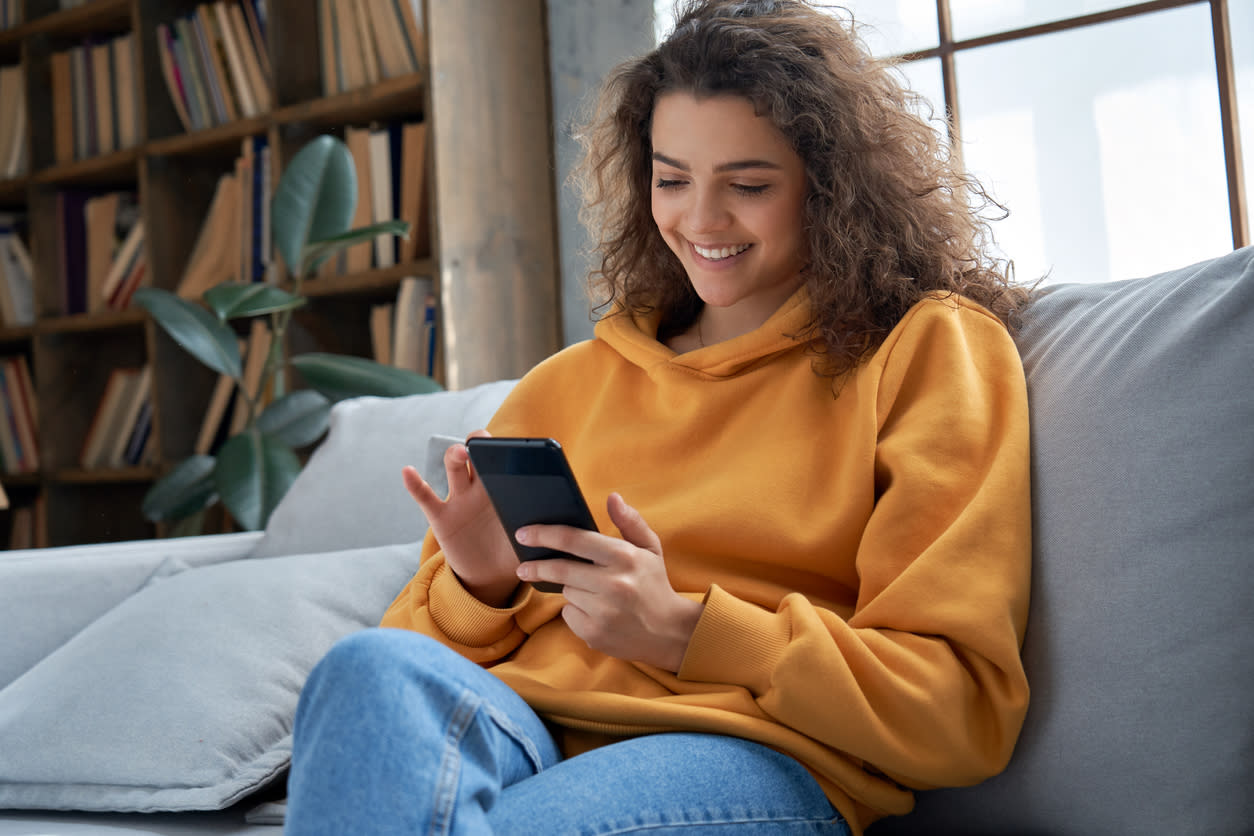 Woman on sitting on couch using her phone