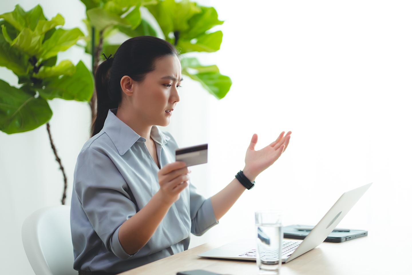 A confused person looking at a gift card and laptop.

